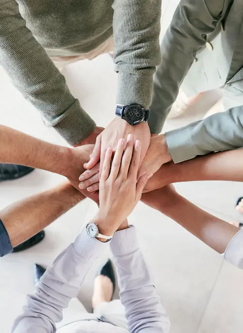 Engineering team members placing their hands together in the center as a gesture of teamwork and collaboration.